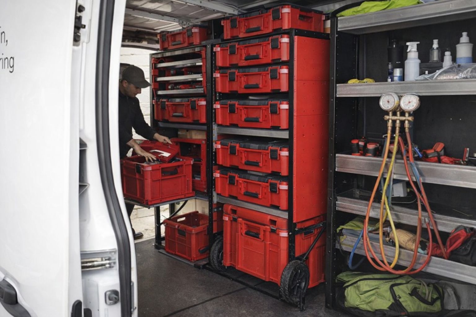 Aménagement d'un utilitaire professionnel avec des étagères et des bacs rouges de rangement.