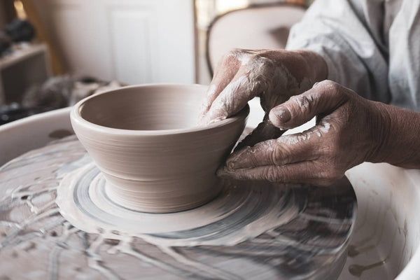Mains façonnant un bol en argile sur un tour de potier